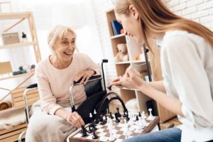 Elderly woman at home playing chess with daughter after successful retirement planning